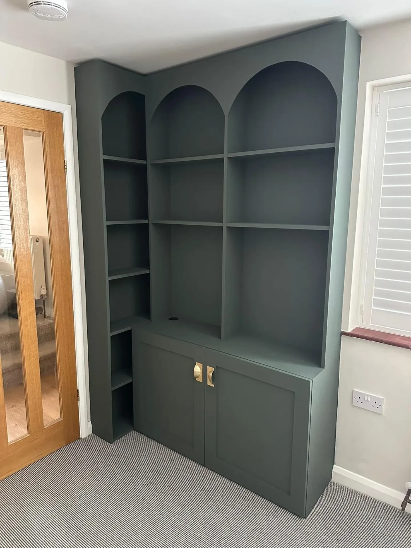 Custom green built-in shelving unit with arched details
